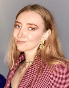 Julia has long blonde hair and is smiling at the camera