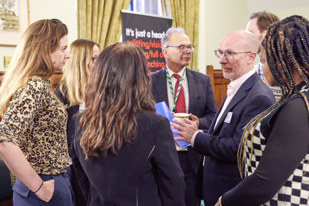 Simon Opher MP and The Migraine Trust chief executive Rob Music are talking to a group of five people who live with migraine 