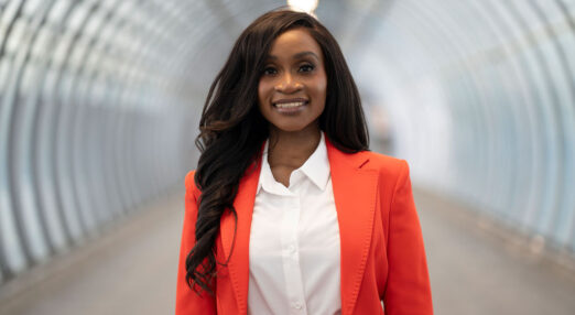 Chisola smiling at the camera in an orange suit