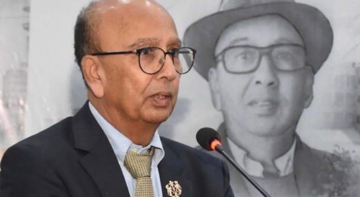 Dr Ahmed stands beside a podium