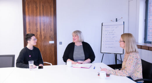 Three people sat at a table in a meeting room